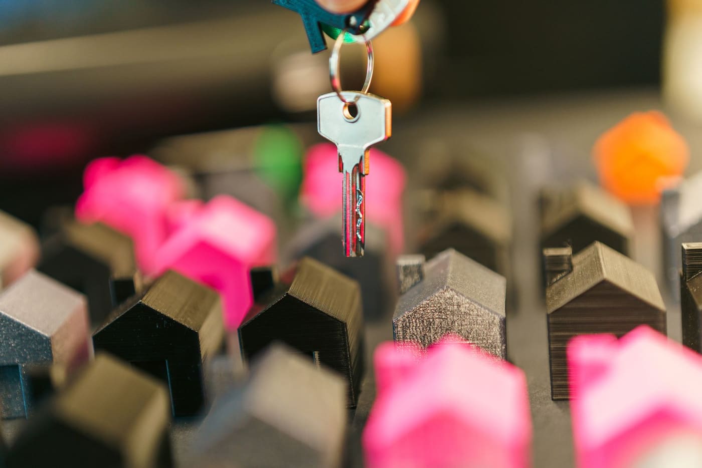 A hand holding a key above small colorful model houses