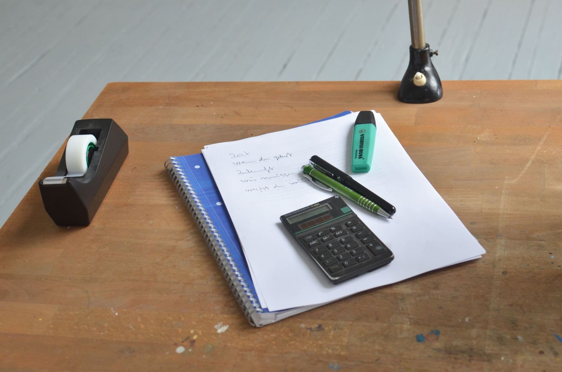 Calculator, notebook and pens on a wooden desk