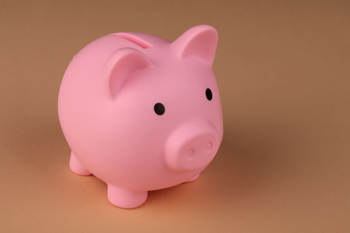 A pink piggy bank on a plain brown background