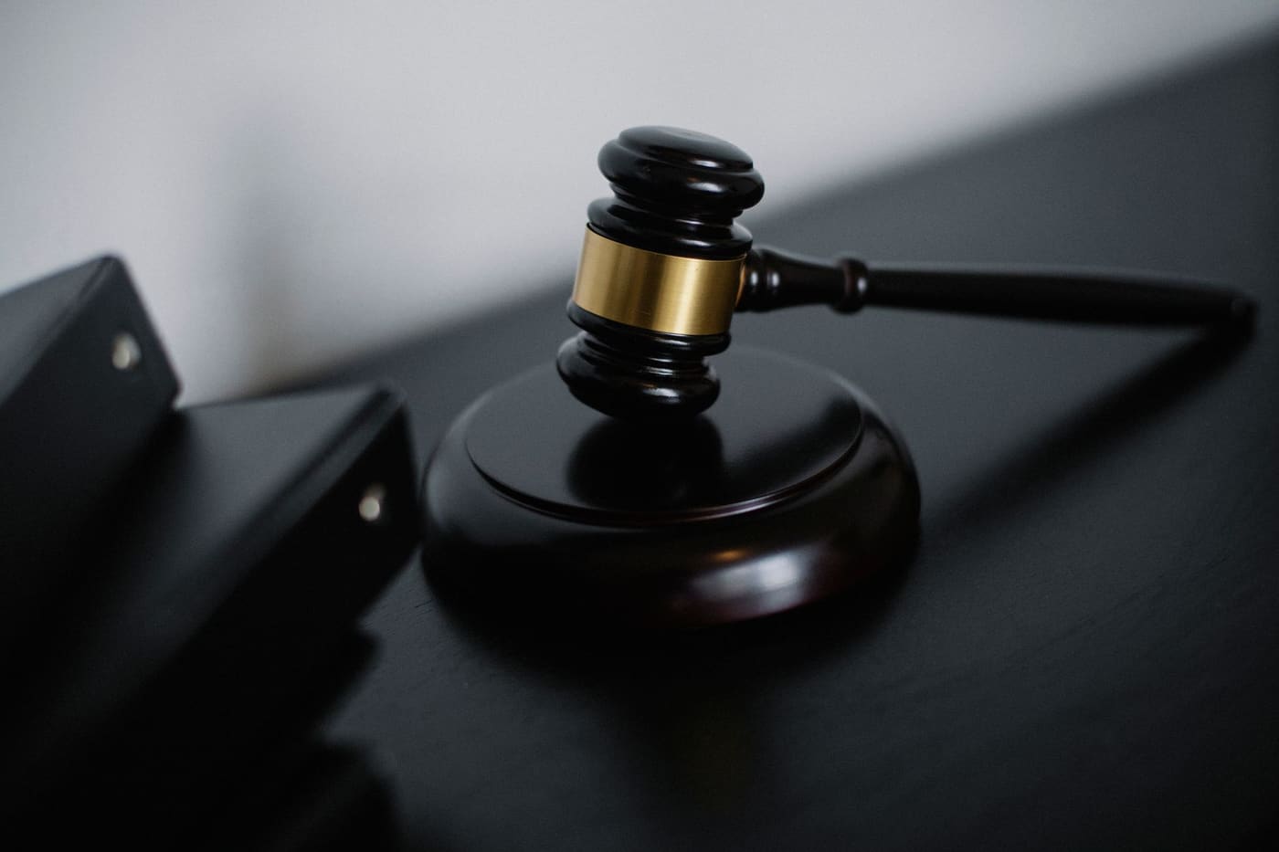 A wooden gavel with a gold band on a dark desk